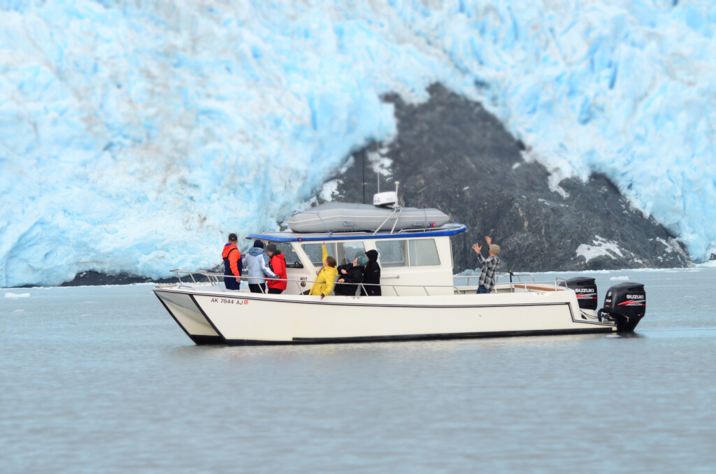 Urayuli sitting in front of Aialik Glacier on a tour to Kenai Fjords